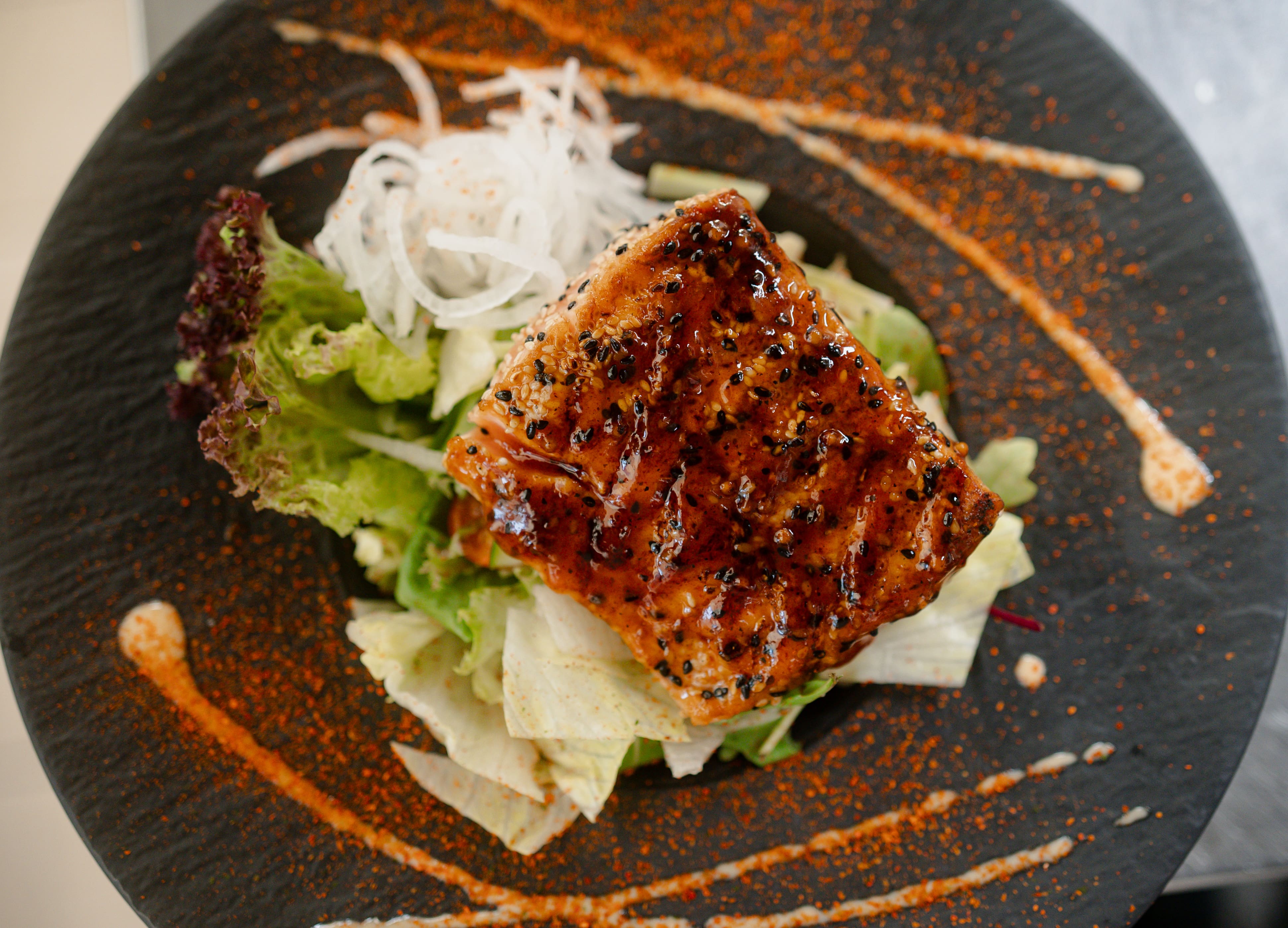 Gegrilltes Lachsfilet auf einem Salatbett garniert mit Teriyaki soße von oben geschossen